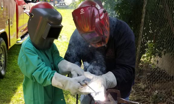 Outdoors, Bridgemania students do actual welding with supervision.