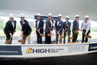 A group of executives celebrates a groundbreaking by scooping a shovelful of earth.
